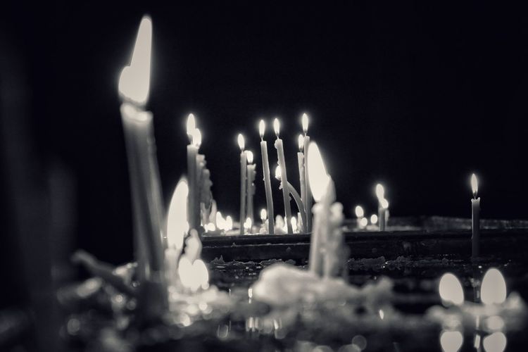 Close-up of lit candles in temple against building