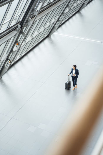 Businesswoman with suitcase walking in corridor