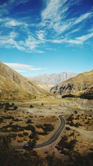 Road leading towards mountains against blue sky