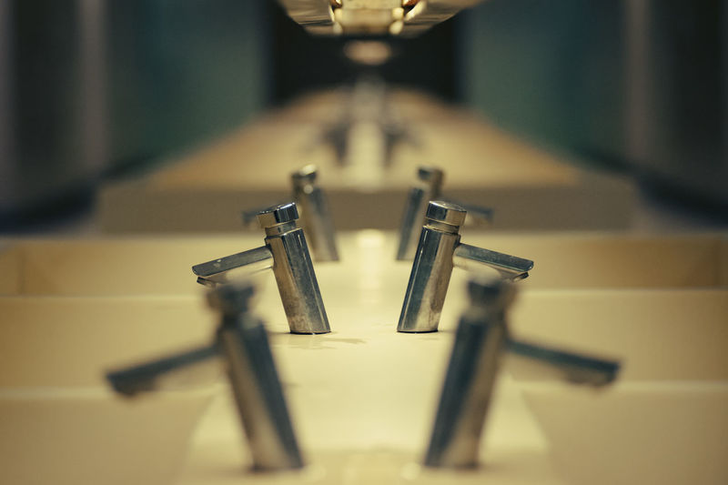 Row of faucets with reflection in restroom