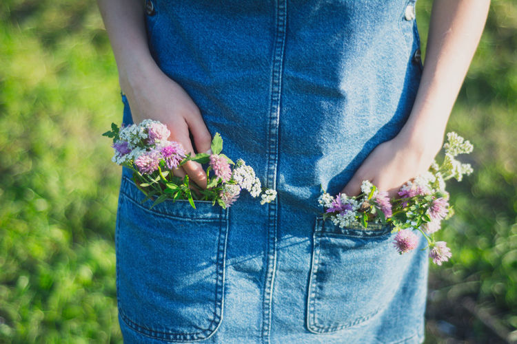 Midsection of woman with flowers in pockets