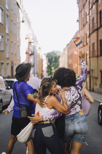 Happy young friends walking on street during gay pride parade