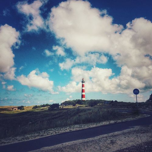 Lighthouse by road against sky