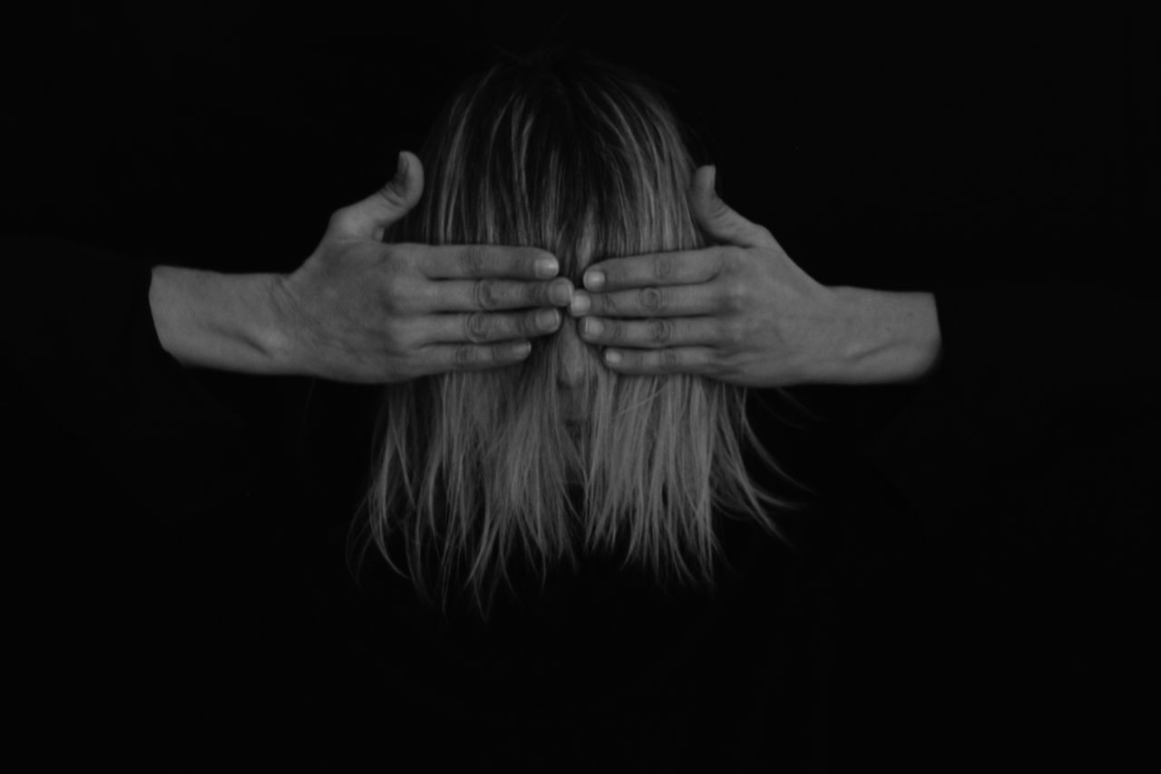 PORTRAIT OF A WOMAN COVERING FACE WITH HAIR