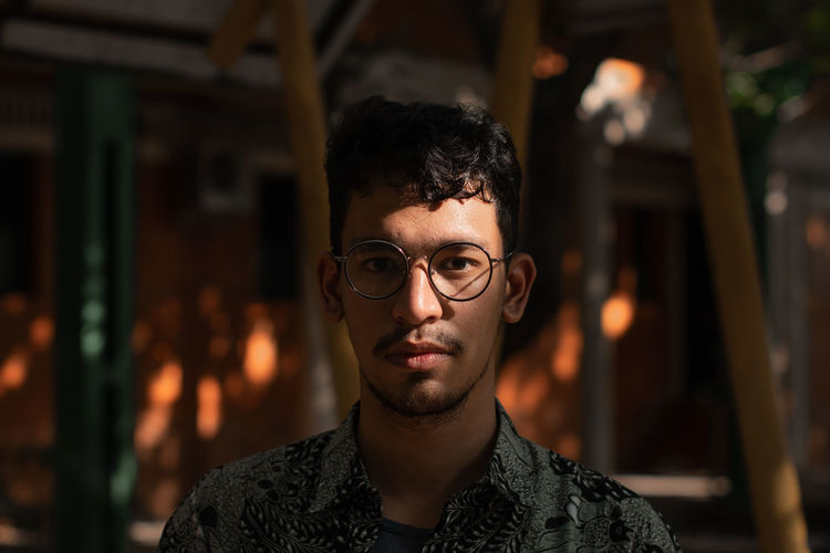 Mixed race man wears round eyeglasses under the shades and sunlight