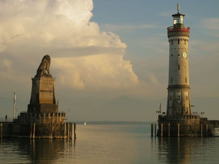 Lighthouse and lion statue against sky at bodensee