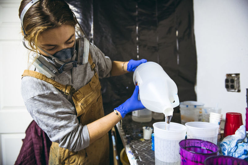 Female resin artist mixing and pouring with respirator mask