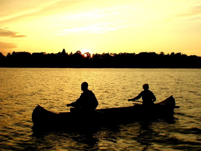 Silhouette of people in boat at sunset