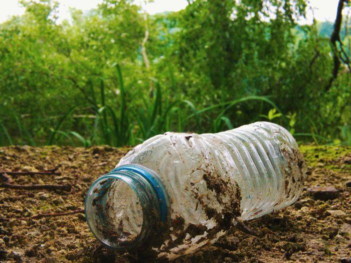 Close-up of abandoned bottle on field