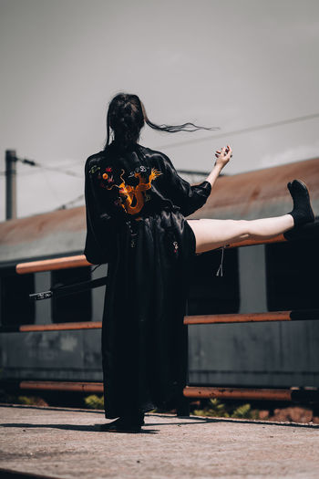 Rear view of woman standing with leg on railing