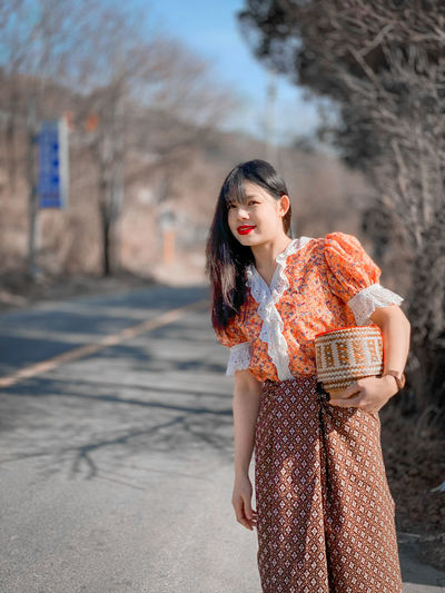 Young woman looking away while standing outdoors