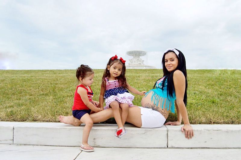 Portrait of pregnant woman and daughters sitting outdoors