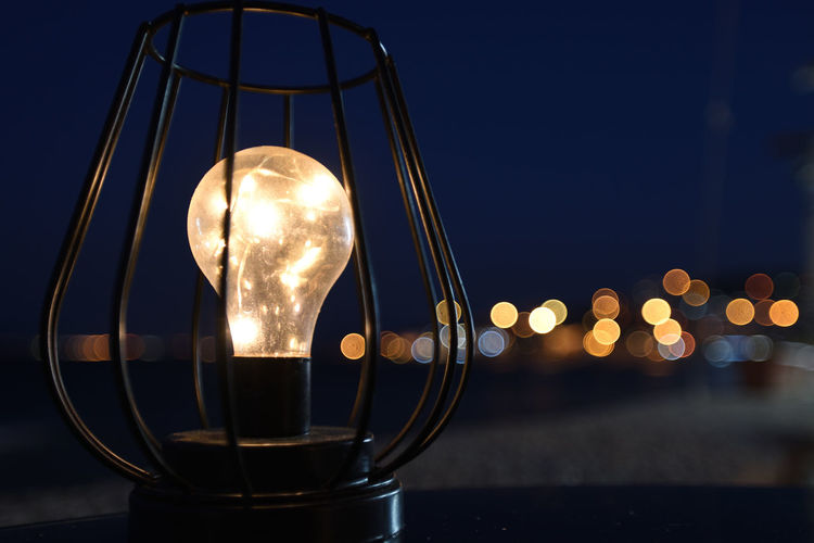 Close-up of illuminated light bulb against clear sky at night