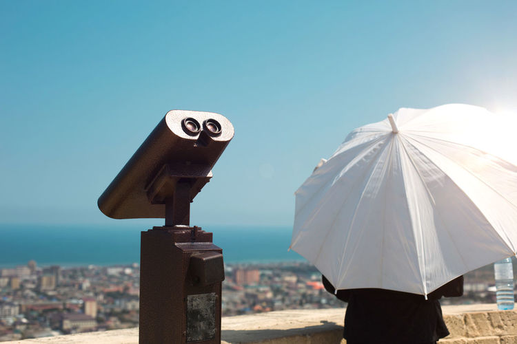 Rear view of woman holding umbrella against sky
