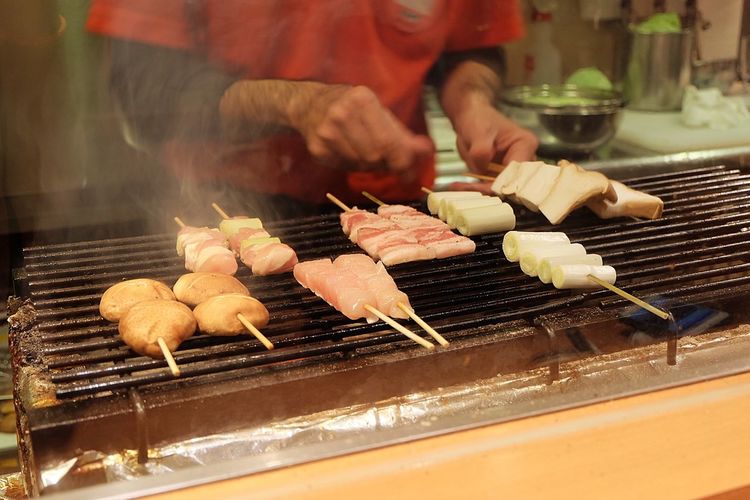 Midsection of man with meat on barbecue grill