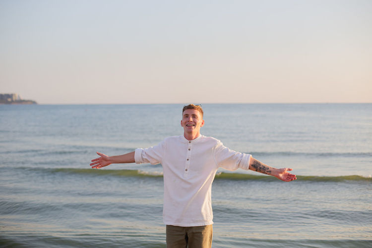 Portrait of man standing at beach against clear sky
