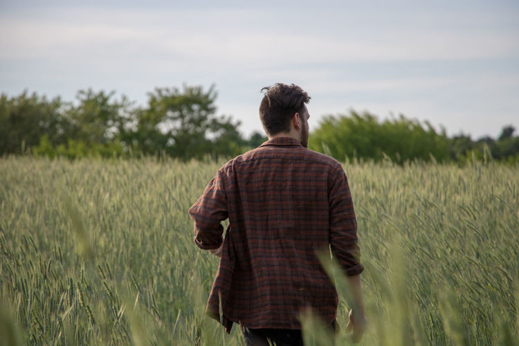 Rear view of young man walking on field