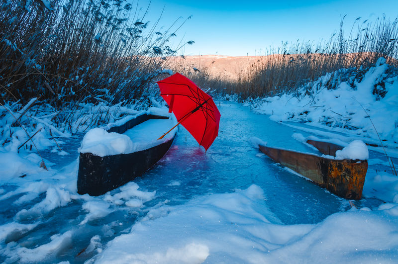 Red umbrella on snow covered field