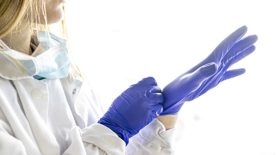 Medicine and surgery theme: female nurse putting on protective blue gloves