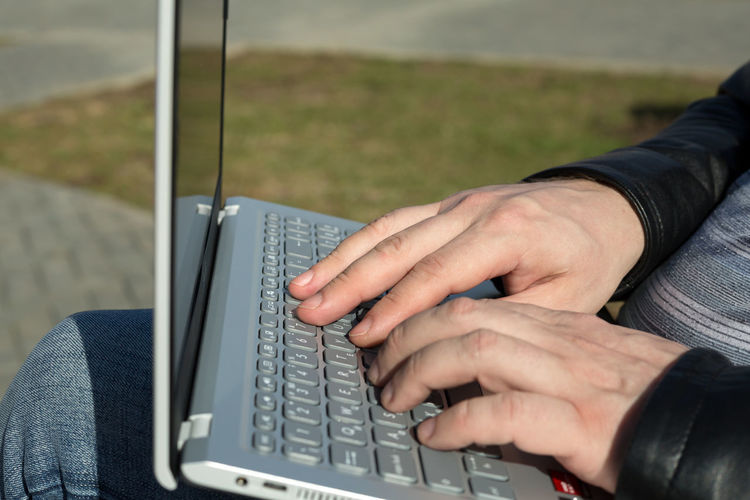 Cropped hands of man using laptop