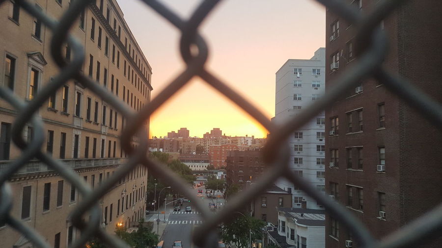 Close-up of cityscape seen through chainlink fence