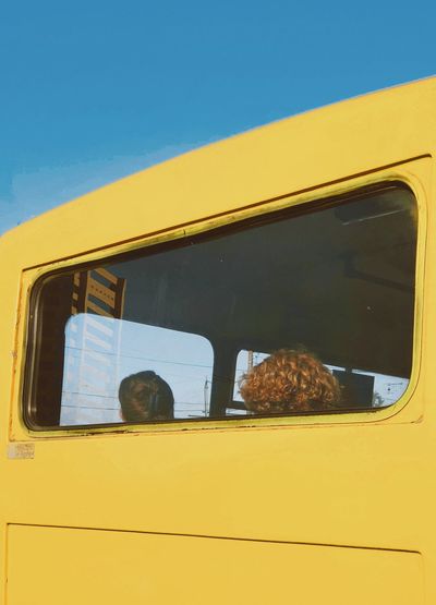 Yellow train against sky seen through glass window