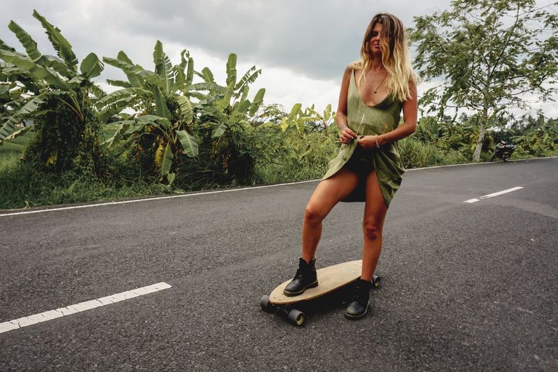 Young woman on skateboard against sky