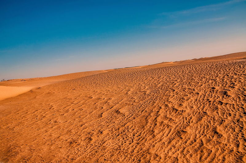 Scenic view of desert against blue sky