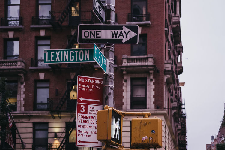 Low angle view of road sign against buildings in city