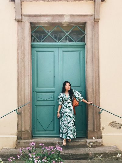 Woman standing against door of building