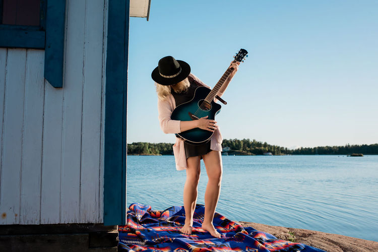Woman playing the guitar whilst at the beach on a sunny day