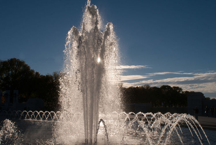 Illuminated fountain in park against sky