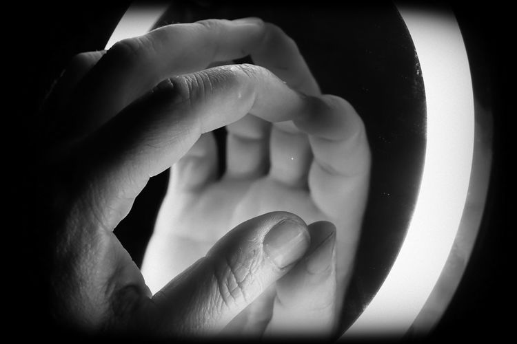 Cropped image of hand on mirror with reflection