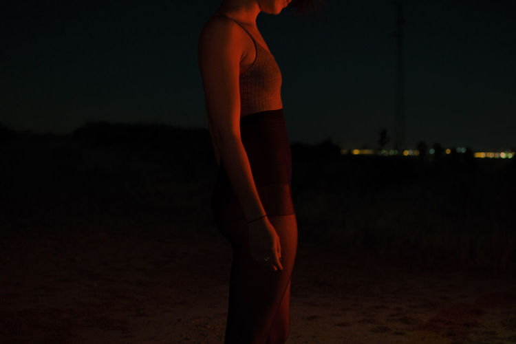 Midsection of sensuous woman standing on field at night