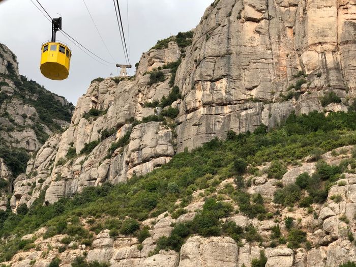Low angle view of overhead cable car against rocky mountains