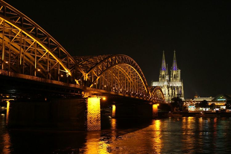 Illuminated hohenzollern bridge over rhine river against cologne cathedral