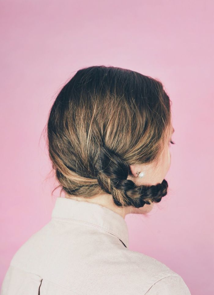 Rear view of woman with braided hair around face against pink wall
