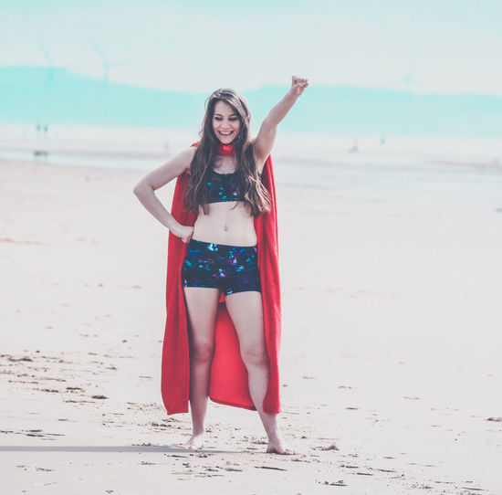Full length of young woman wearing cape while standing at beach