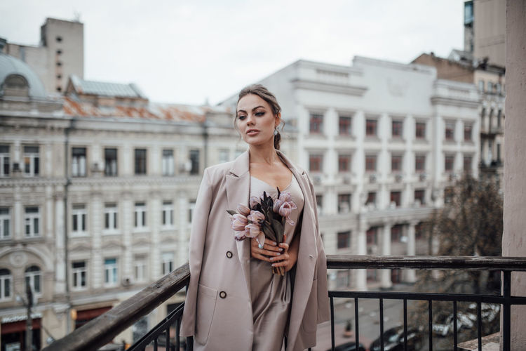 Portrait of woman standing against building in city