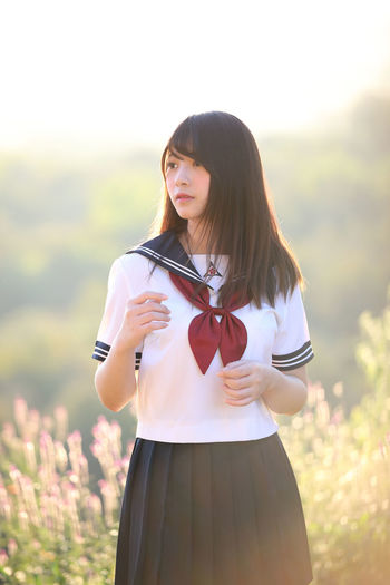 Beautiful young woman wearing uniform while standing on land