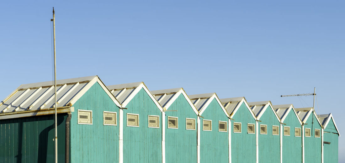Beach huts against clear blue sky