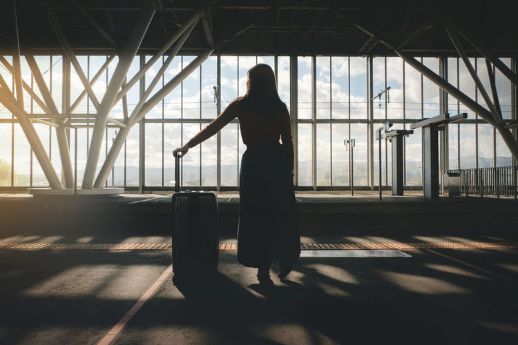 Woman with luggage standing at airport departure area