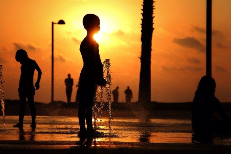 People playing in water at sunset