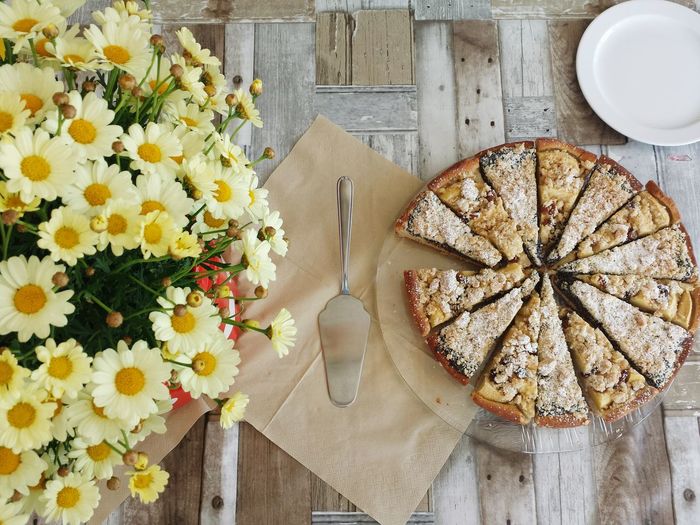 High angle view of flowers and tart on wooden table