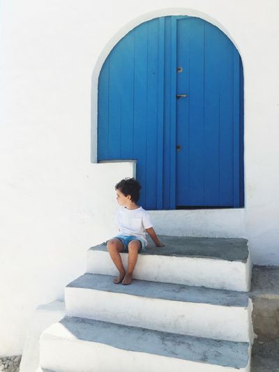Boy looking away while sitting on staircase against wall