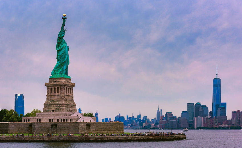 Statue of liberty against cityscape and sky during sunset