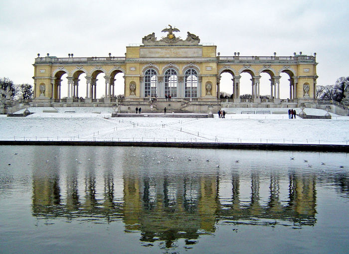 Reflection of gloriette monument in pond at schonbrunn palace during winter