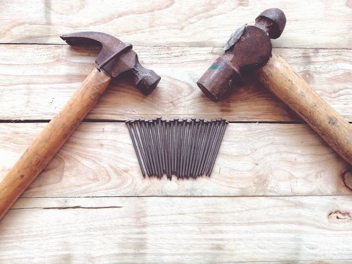 High angle view of nails and hammers on wooden table