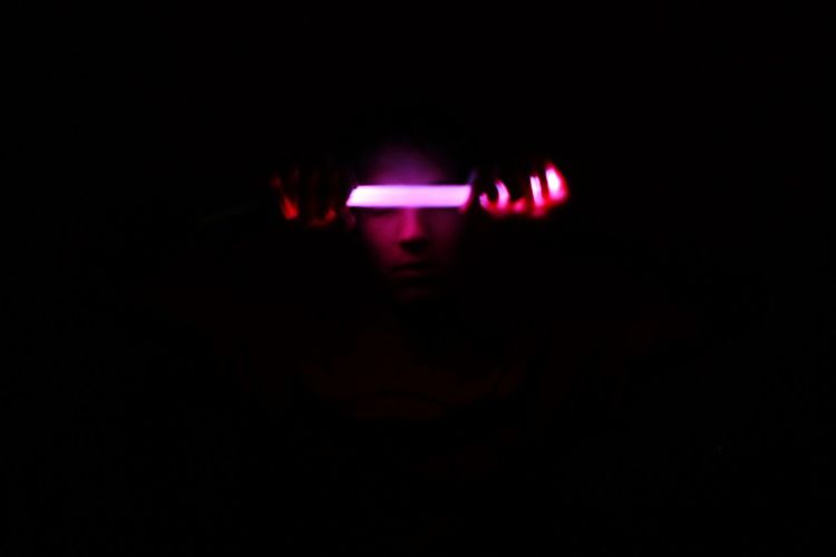 Close-up of illuminated person in darkroom