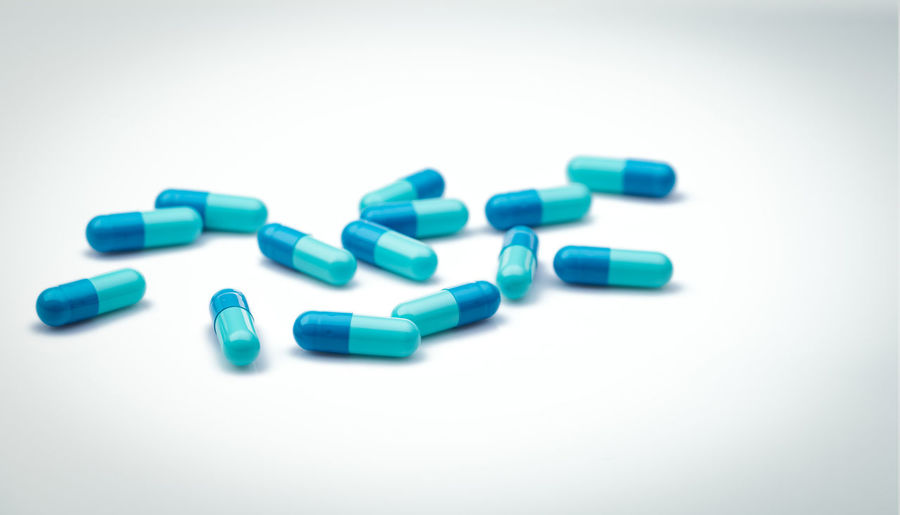Selective focus on blue capsule pills. group of capsule pills with shadow spread on white background